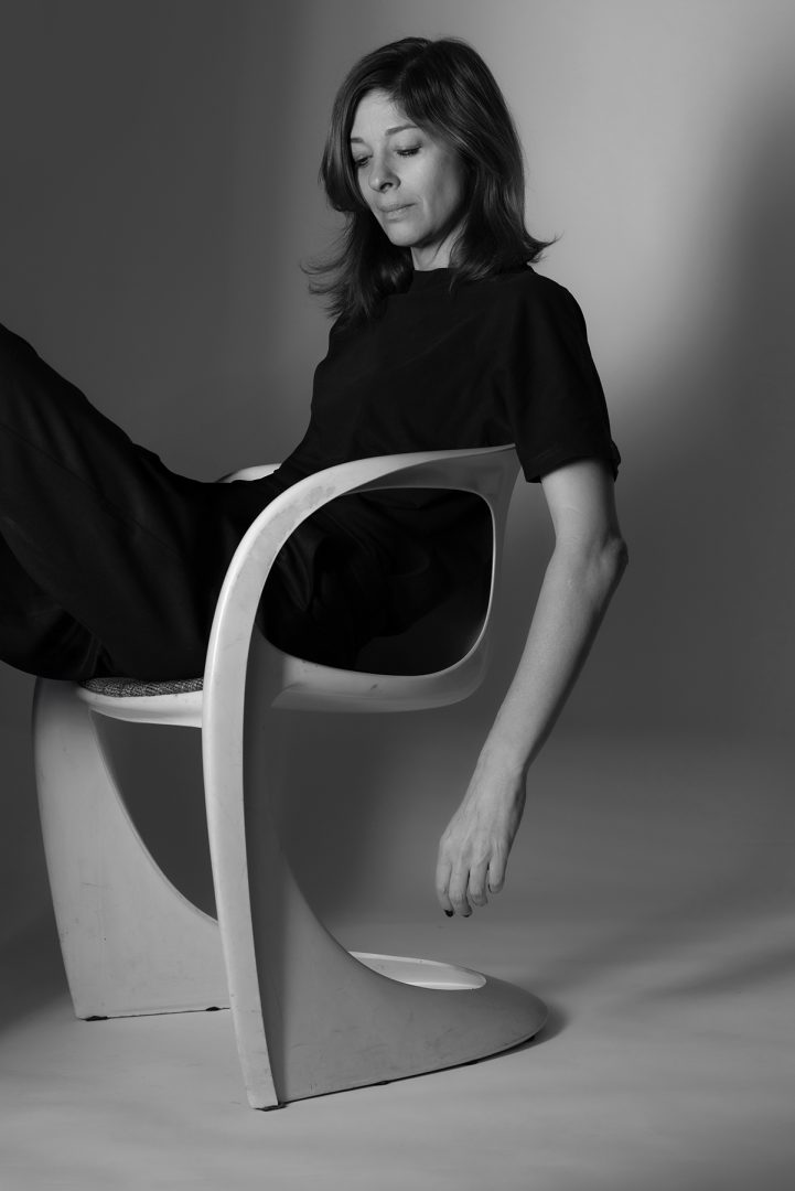 Zsu Szabo sitzt auf einem Stuhl im Fotostudio